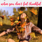 Woman sitting in fall leaves throwing them in the air