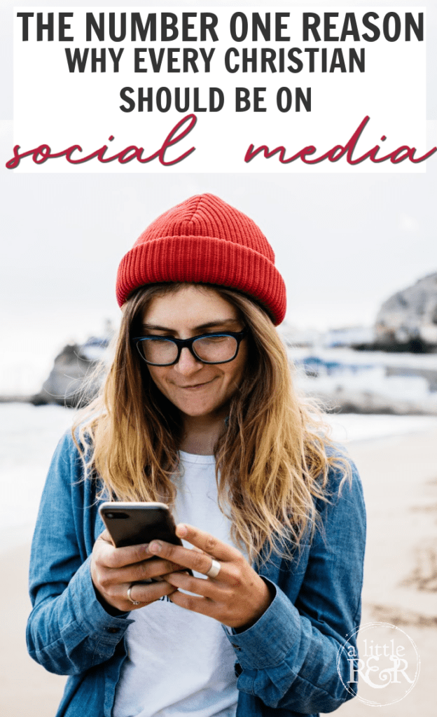 lady in red winter cap, blue sweater, on a beach looking at phone