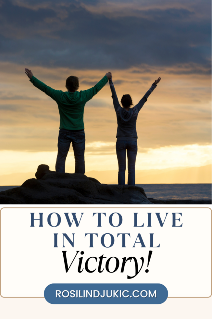 A couple on top of a hill with arms raised learning how to live in total victory