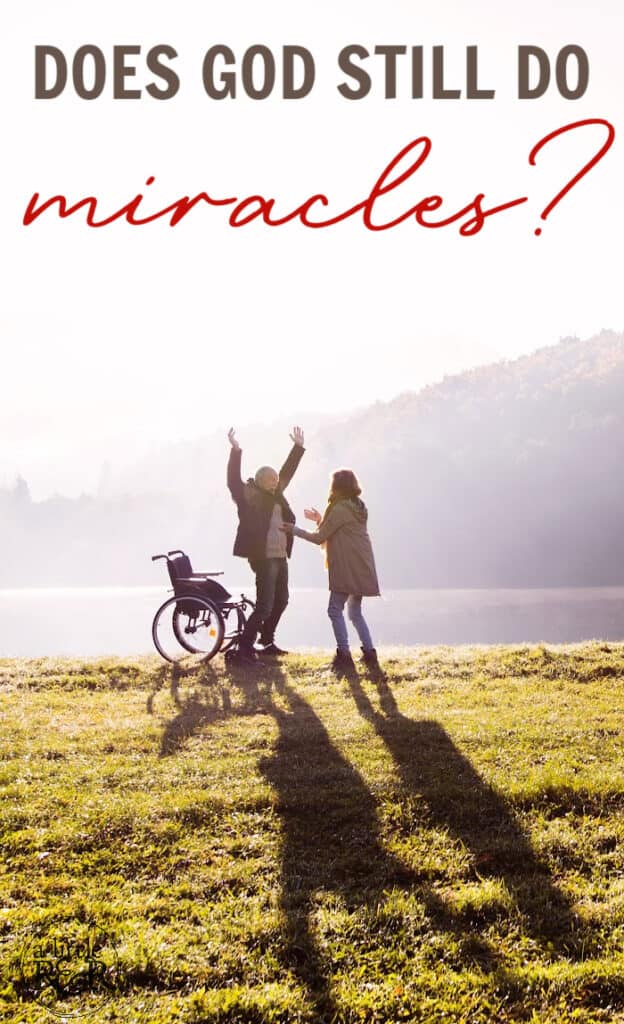 woman praying for man standing up from a wheel chair - out in a field