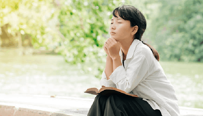 person praying with Bible on lap