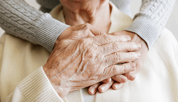 Persons hands on the heart of an elderly person caring for them