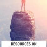 Woman standing on cliff with arms raised