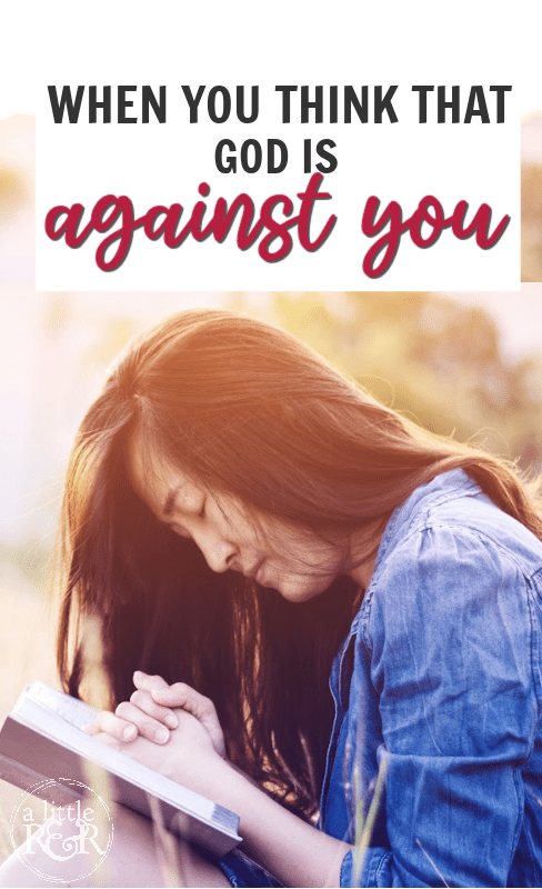 woman in blue shirt with hands folded on Bible praying