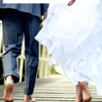 bride and groom running across wooden bridge barefoot