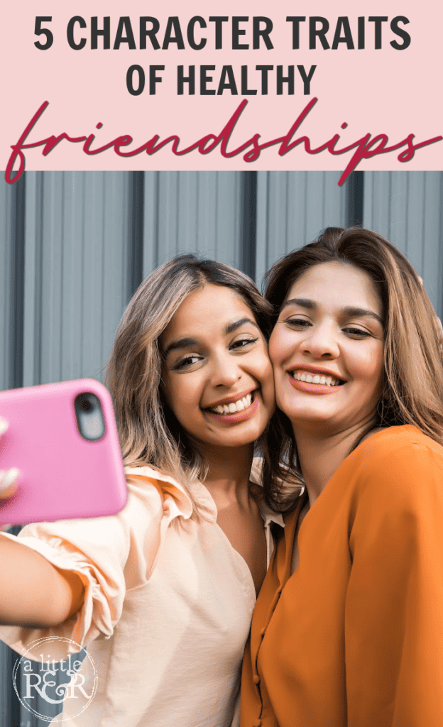 Two ladies in front of metal building taking a selfie with a pink phone