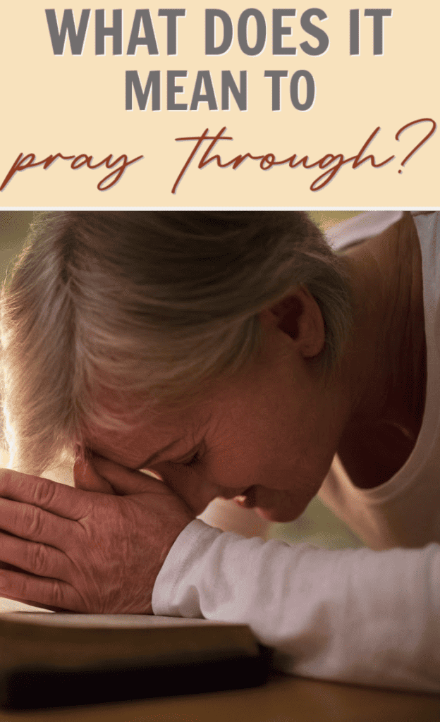 woman with head on folded hands bowed over a Bible praying