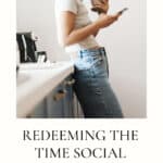 Woman leaning against kitchen sink looking at her phone