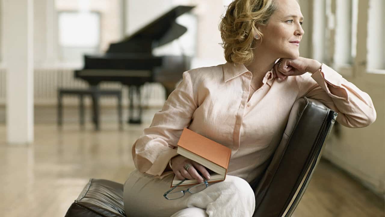 Woman sitting with book in her lap thinking and renewing the ind