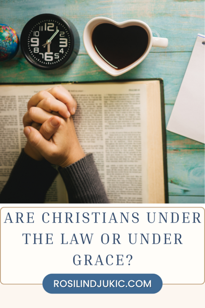 a person with their hands on the Bible - are Christians under the law or under grace